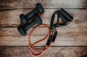 A person stretching on a yoga mat at home, surrounded by fitness equipment like a foam roller and resistance bands.