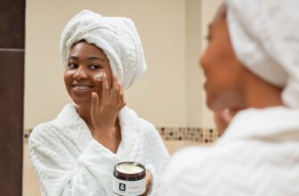 A close-up of a person's hands applying moisturizer on their face, showcasing a healthy skincare routine.
