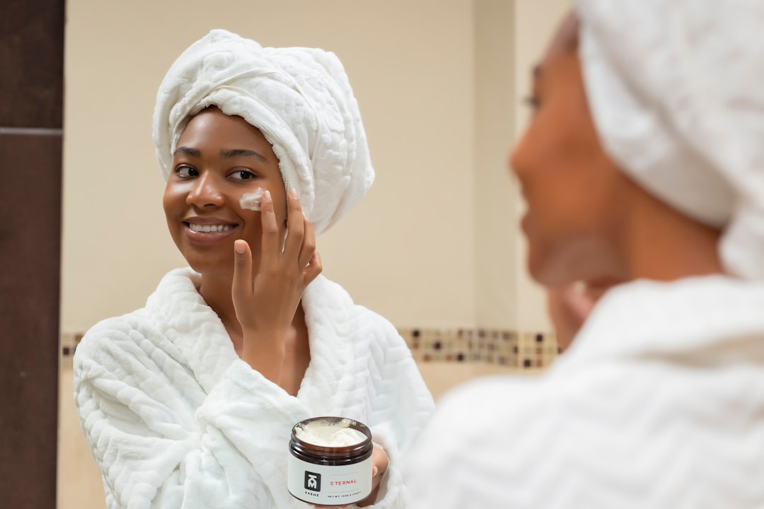 A close-up of a person's hands applying moisturizer on their face, showcasing a healthy skincare routine.
