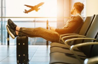 A person stretching or doing light exercises in an airport or bus station, surrounded by travel bags and gear.